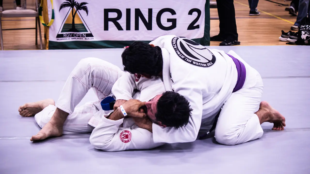 Two adult competitors in white gis grappling on the mat at Ring 2 of an RGV Open.