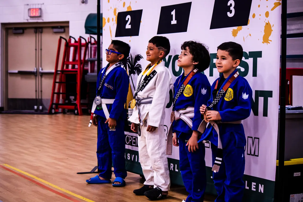 Four young competitors in gis stand on the RGV Open podium wearing their medals.